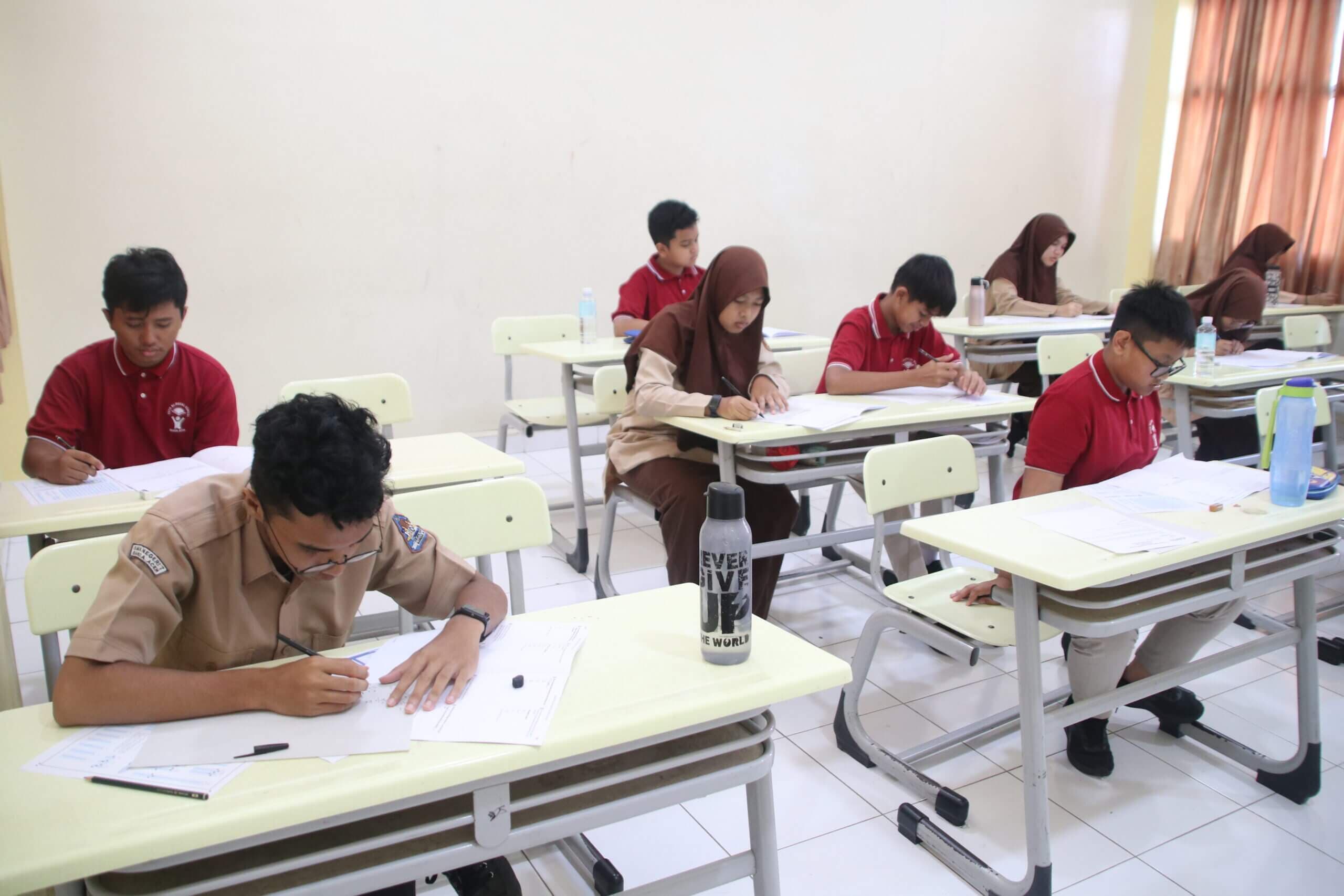 Students concentrating on their EMC competition papers in a classroom