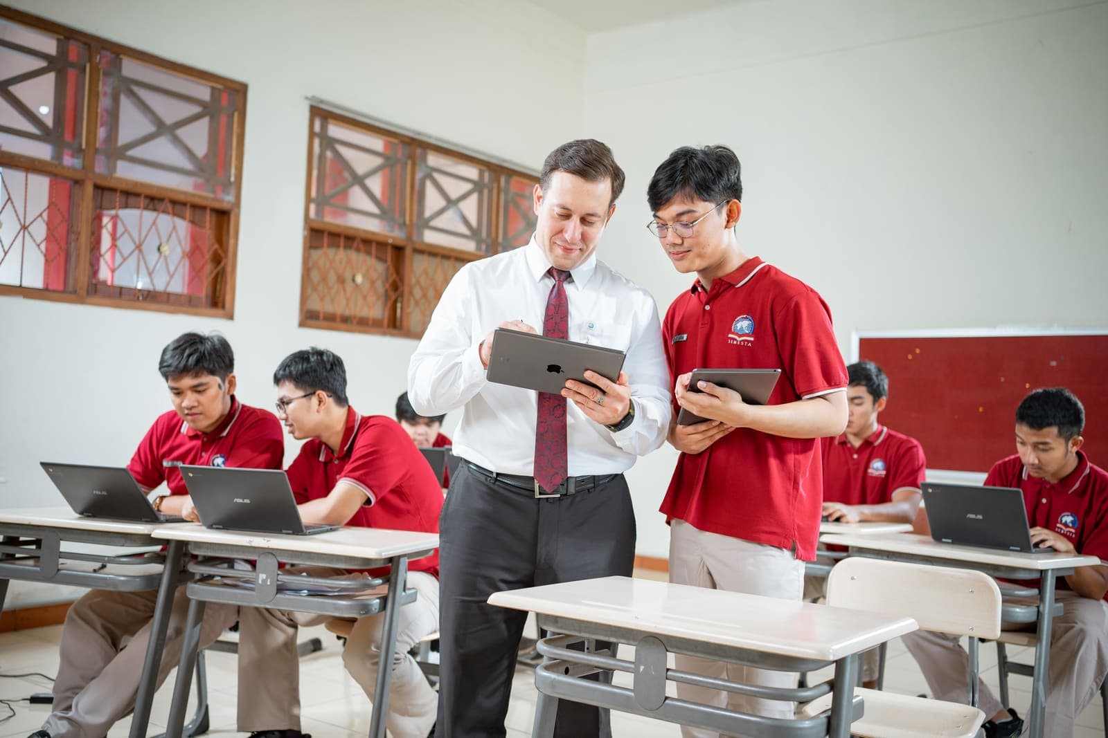 A teacher and student reviewing work together on a tablet