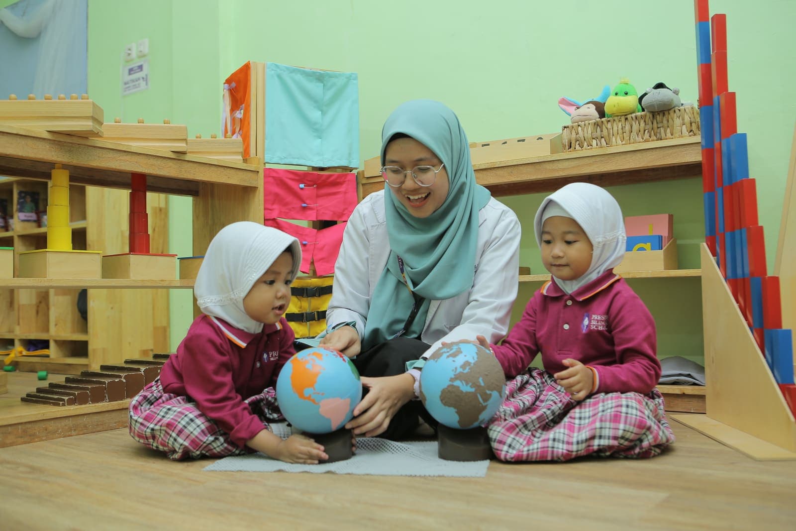 A teacher and toddlers exploring globes on the classroom floor