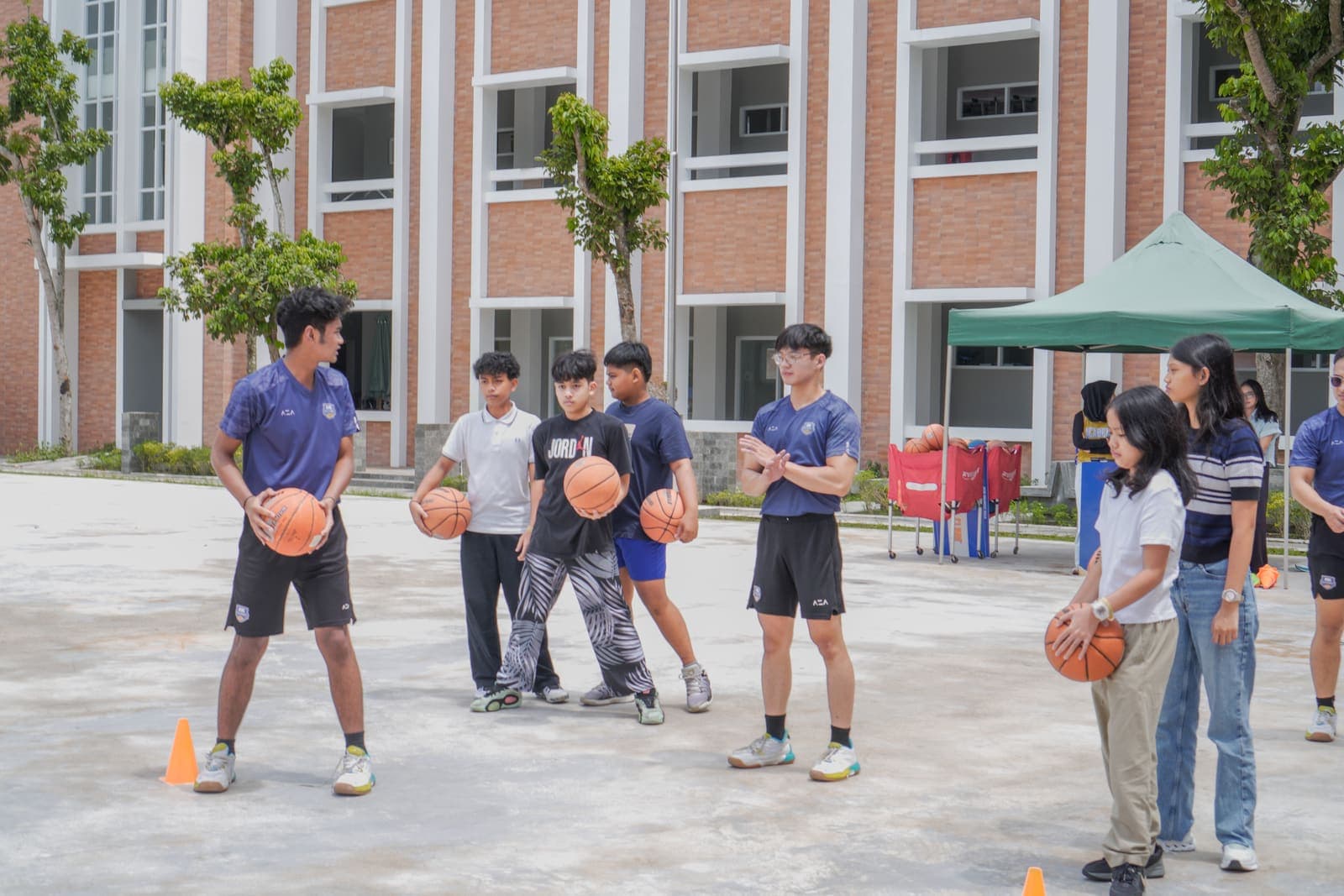 A basketball clinic in front of a red-brick campus building